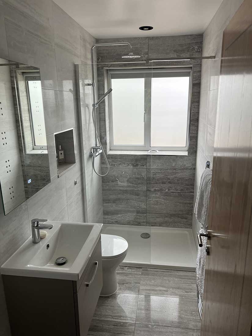 Walk-in shower with marble-effect tiling and glass screen fitted by Overflow in Berkshire